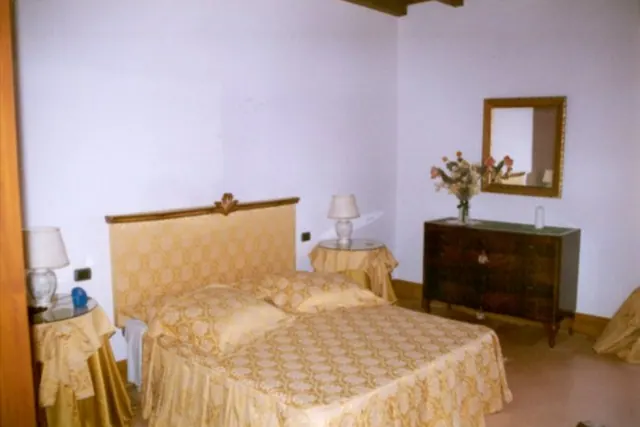 La camera Oro: letto matrimoniale in tessuto dorato, comò antico con specchio e fiori