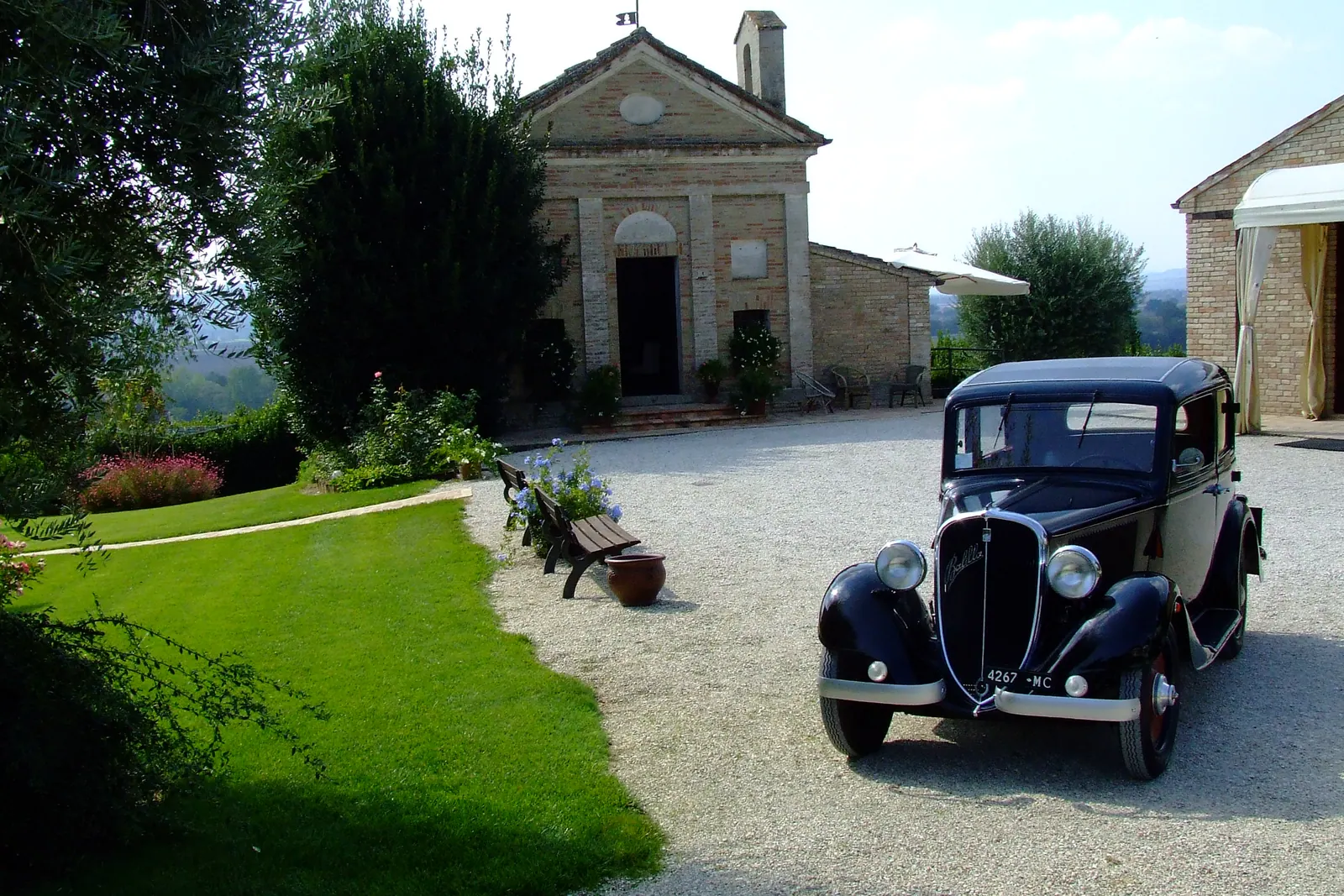 Un'auto d'epoca nera parcheggiata davanti alla chiesetta della villa
